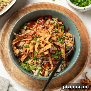 A ground turkey egg roll bowl with a fork and green onions on top.